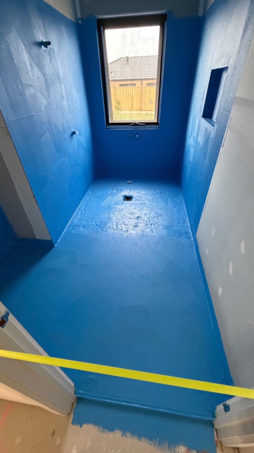 Client project showing blue waterproofing membrane across shower walls and floor